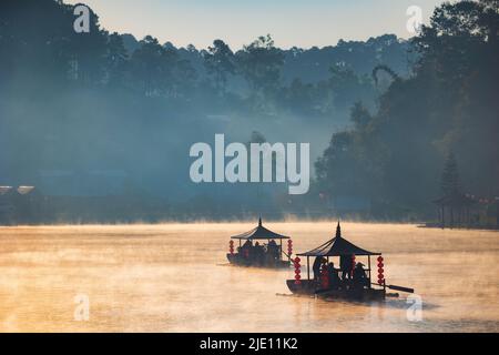 Giro turistico in barca cinese all'alba con nebbia sul lago Ban Rak Thai, Thailandia Foto Stock