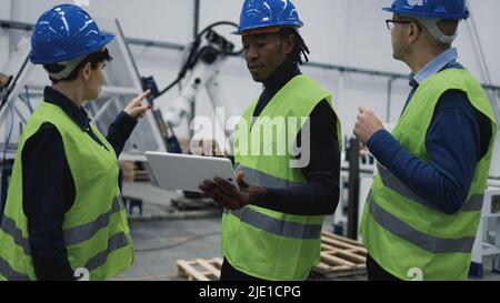 Team di ingegneri che lavorano nella fabbrica robotica per monitorare il progetto sul tablet - concetto di settore tecnologico Foto Stock