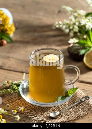 Tè alla menta fresco. Tè alla menta e al limone. Tazza di tè alle erbe su tavola di legno. Vista verticale Foto Stock