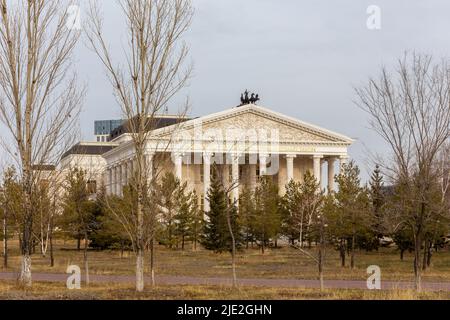 Nur Sultan (Astana), Kazakistan, 11.11.21. Astana Opera edificio in stile classico con ornamenti dorati, sculture e colonne viste tra gli alberi. Foto Stock