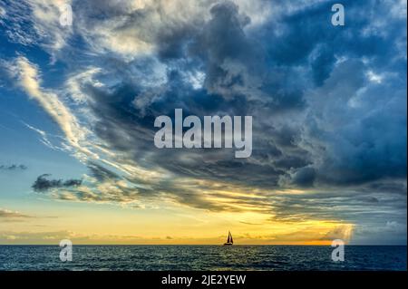 Una tempesta si sta avvicinando in alto mentre Una piccola imbarcazione si sposta verso la luce brillante Foto Stock