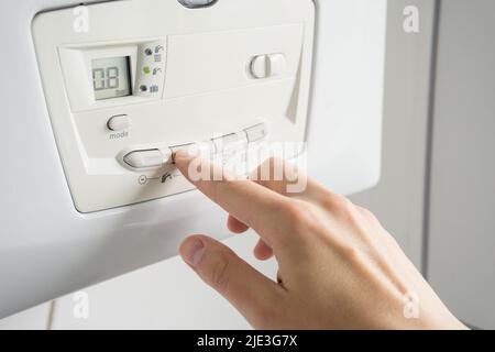 Temperatura di regolazione uomo su una caldaia di riscaldamento. Foto Stock