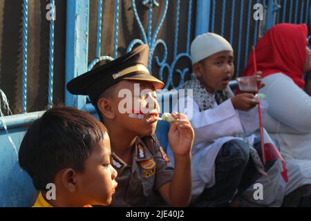 Jakarta, Indonesia - 08 18 2019: Bambini piccoli seduti a riposare mentre mangiano spuntini dopo aver completato la sfilata che celebra l'Independe Indonesia del 73rd Foto Stock