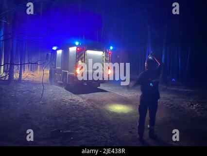 Kosilenzien, Germania. 25th giugno 2022. I vigili del fuoco si riuniscono di notte durante la loro missione nella foresta bruciata vicino a Kosilenzien. Il grande incendio boschivo al confine tra Sassonia e Brandeburgo continuerà ad occupare i servizi di emergenza questo sabato. Venerdì sera tardi, tuttavia, ci sono stati chiari segni di sollievo. Le task force erano riuscite a tenere sotto controllo le fiamme in misura tale da escludere in gran parte un ulteriore pericolo per le località evacuate di Kröbeln e Kosilenzien. Credit: Julius-Christian Schreiner/dpa/Alamy Live News Foto Stock