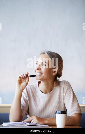 Reamy entusiasta giornalista freelance con capelli color cenere seduti a tavola e pensando a nuove idee per l'articolo Foto Stock