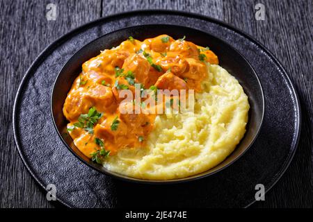 nakkikastike, salsicce in salsa di pomodoro cremosa con purè di patate in ciotola nera, cucina finlandese, vista orizzontale dall'alto Foto Stock