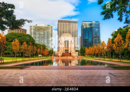 Il Central Hyde Park nel CBD di Sydney in autunno lascia la stagione autunnale attorno al monumento ai caduti e allo stagno che riflette alte torri. Foto Stock