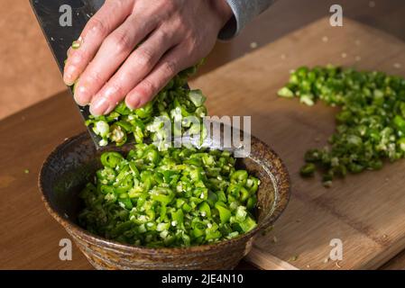 Coltello da cucina dello chef sul peperoncino verde hangzhou in ciotole Foto Stock