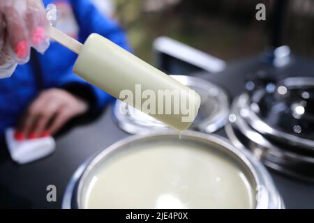 Persona che tuffa il gelato in cioccolato bianco nel caffè Foto Stock