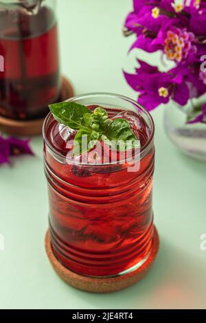 Tè di frutta rossa ghiacciata appena fatto su un tavolo verde Foto Stock