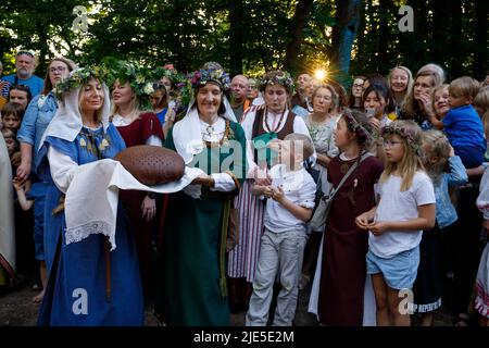 Le donne in costumi nazionali lituani eseguono rituali con pane di segale appena sfornato, durante la celebrazione Midsummer Festival a Vilnius Foto Stock