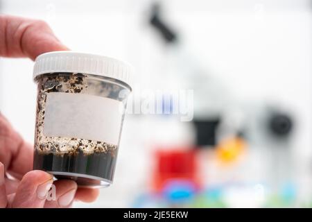 l'ecologo scientifico contiene un contenitore con un campione di terreno per analisi chimiche e microbiologiche Foto Stock