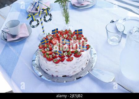 La celebrazione della vigilia svedese di mezza estate il venerdì. Ecco una torta di fragole con bandiere svedesi. Foto Stock