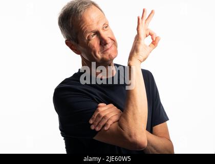 Un uomo anziano attivo in una maglietta blu sorridente, con un atteggiamento positivo su sfondo bianco Foto Stock