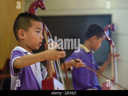 (220625) -- BAOTOU, 25 giugno 2022 (Xinhua) -- gli studenti imparano a suonare Morin khuur, un tradizionale strumento ad arco mongolo che presenta un'incisione con testa di cavallo nella sua parte superiore, durante un'attività post-lezione in una scuola primaria a Baotou, nella Regione Autonoma Mongolia interna della Cina settentrionale, 24 giugno 2022. Le scuole di Baotou hanno organizzato varie attività dopo le lezioni per arricchire il tempo scolastico degli studenti. (Xinhua/Peng Yuan) Foto Stock