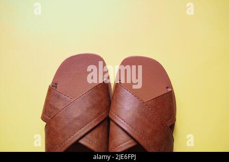 Top view marrone estate scarpe in pelle, sandali da donna su sfondo giallo Foto Stock