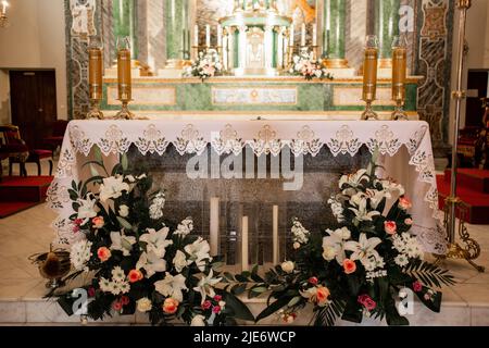 candele e fiori in una chiesa cattolica Foto Stock