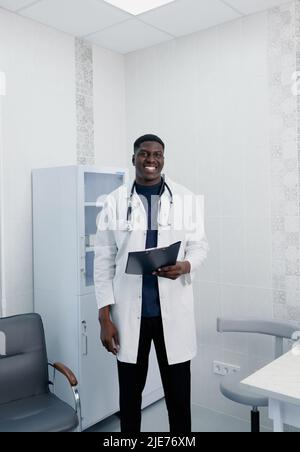Una foto di un bel medico giovane che si trova in piedi da solo nella sua clinica. Foto Stock