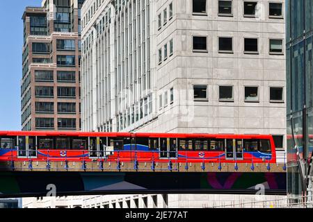 Londra, Inghilterra - Giugno 2022: Treno passeggeri senza conducente della Docklands Light Railway passando per gli edifici di uffici a Canary Wharf Foto Stock