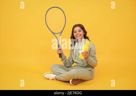 happy bambino tenere badminton racchetta e bere acqua da bottiglia su sfondo giallo, salute. Foto Stock