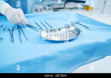 Operatore medico che afferra gli attrezzi sterili dal vassoio Foto Stock