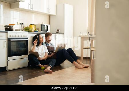 Casalinga e blogger seduti sul piano della cucina Foto Stock