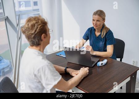 Il medico sorridente compila il modulo di rapporto medico sulle cure mediche dei pazienti durante l'appuntamento Foto Stock