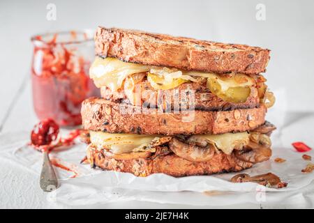 Toast fatti in casa e gustosi con formaggio, cipolla e funghi. Toast con salsa rossa, funghi e formaggio. Foto Stock