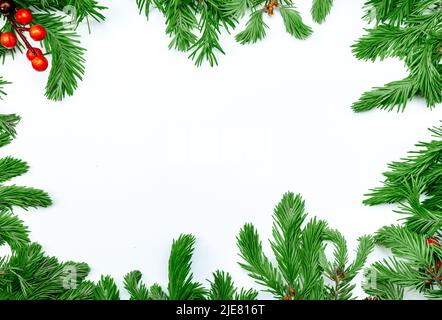 Composizione di Natale e Capodanno. Vista dall'alto di rami di abete rosso e bacche rosse su sfondo bianco. Cornice natalizia in abete scuro, cono Foto Stock