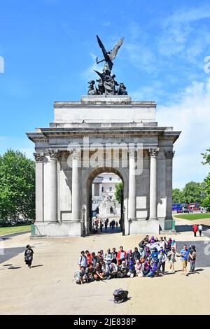 I turisti si posizionano per un grande gruppo di foto o film di fronte allo storico Wellington Arch e Quadriga Hyde Park Corner London England UK Foto Stock