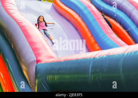 Un bambino allegro gioca in un castello gonfiabile Foto Stock