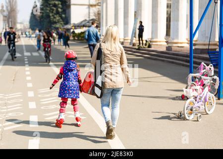 Madre e sua figlia che indossano pattini a rotelle nel parco Foto Stock