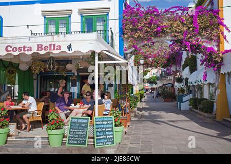 Ristoranti e bar sul lungomare del porto, decorazione di fiori su archi nei vicoli di Puerto de Mogan, Gran Canaria, isole Canarie, Spagna Foto Stock