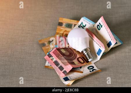 Diverse bollette in euro con una lampadina che rappresentano l'aumento del prezzo dell'elettricità. Foto di alta qualità Foto Stock