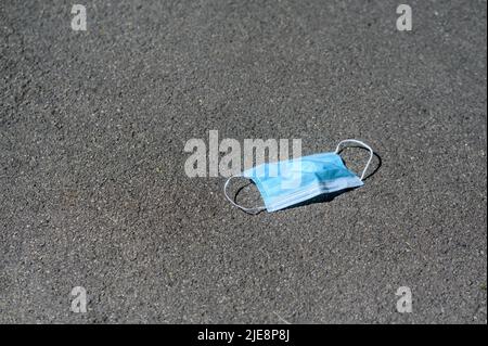 una maschera medica usa e getta si trova sul marciapiede nel parco. Foto Stock