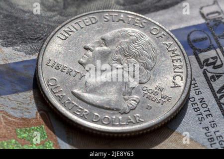 primo piano della moneta da un quarto di dollaro che giace su una banconota da cento dollari Foto Stock