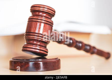 Libro di legge aperto con un gavel di legno dei giudici sul tavolo in una stanza di tribunale o nell'ufficio di applicazione della legge Foto Stock