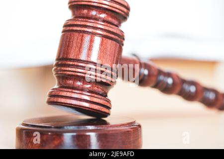 Libro di legge aperto con un gavel di legno dei giudici sul tavolo in una stanza di tribunale o nell'ufficio di applicazione della legge Foto Stock