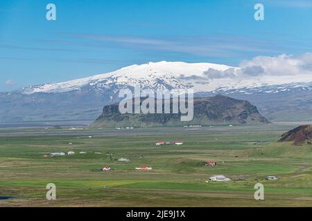 Vista panoramica nel sud dell'Islanda con montagna di tufo Petursey e il vulcano Eyafjiallajokull sullo sfondo Foto Stock