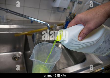 un liquido verde al neon viene messo in un bagno d'acqua Foto Stock