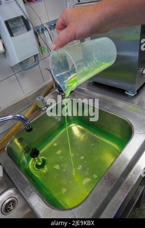 un liquido verde al neon viene messo in un bagno d'acqua Foto Stock