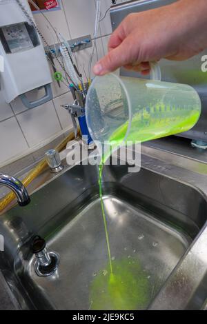 un liquido verde al neon viene messo in un bagno d'acqua Foto Stock