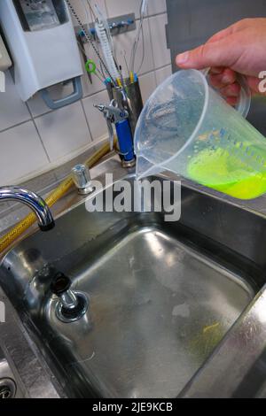 un liquido verde al neon viene messo in un bagno d'acqua Foto Stock