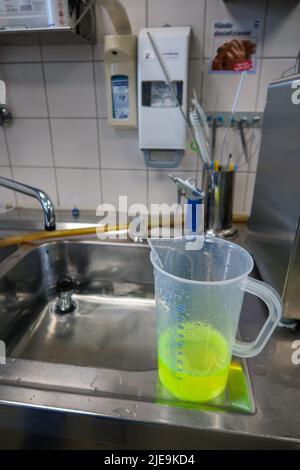 un liquido verde al neon viene messo in un bagno d'acqua Foto Stock