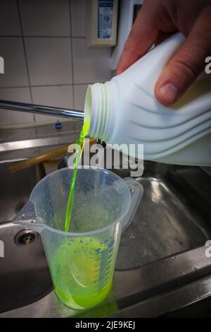 un liquido verde al neon viene messo in un bagno d'acqua Foto Stock