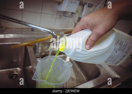 un liquido verde al neon viene messo in un bagno d'acqua Foto Stock