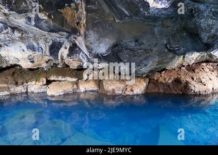 Ammira la grotta di lava di Grjotagja con acque cristalline e blu Foto Stock