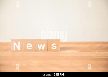 Personaggi news. News. Novità. Scritto su quattro blocchi di legno posti su un tavolo di legno. Lettere bianche. Foto Stock