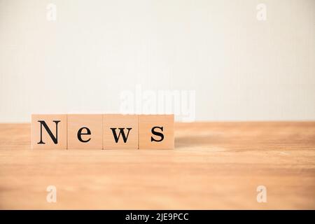 Personaggi news. News. Novità. Scritto su quattro blocchi di legno posti su un tavolo di legno. Lettere nere. Foto Stock