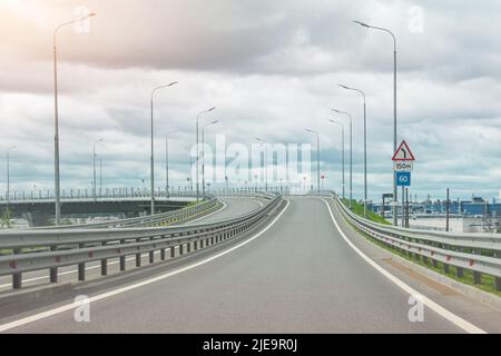 L'uscita dall'autostrada è libera dalle auto, c'è un incrocio di strada davanti al ponte. Con indicatore di direzione e limite di velocità Foto Stock